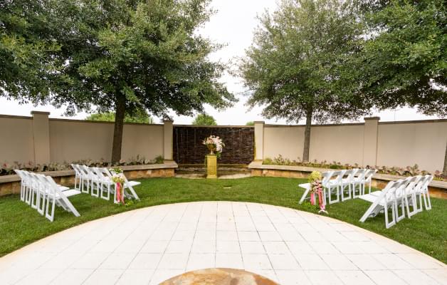 Small outdoor wedding ceremony with trees, empty white chairs, and flowers